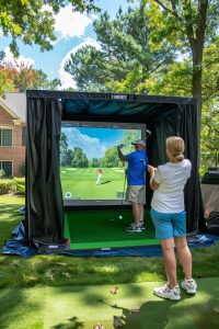 A mobile golf simulator set up in a backyard, with people having a great time playing